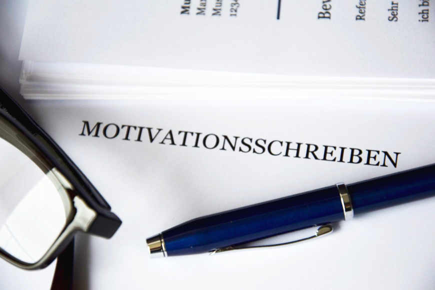 Stift und Brille, die auf Motivationsschreiben liegen