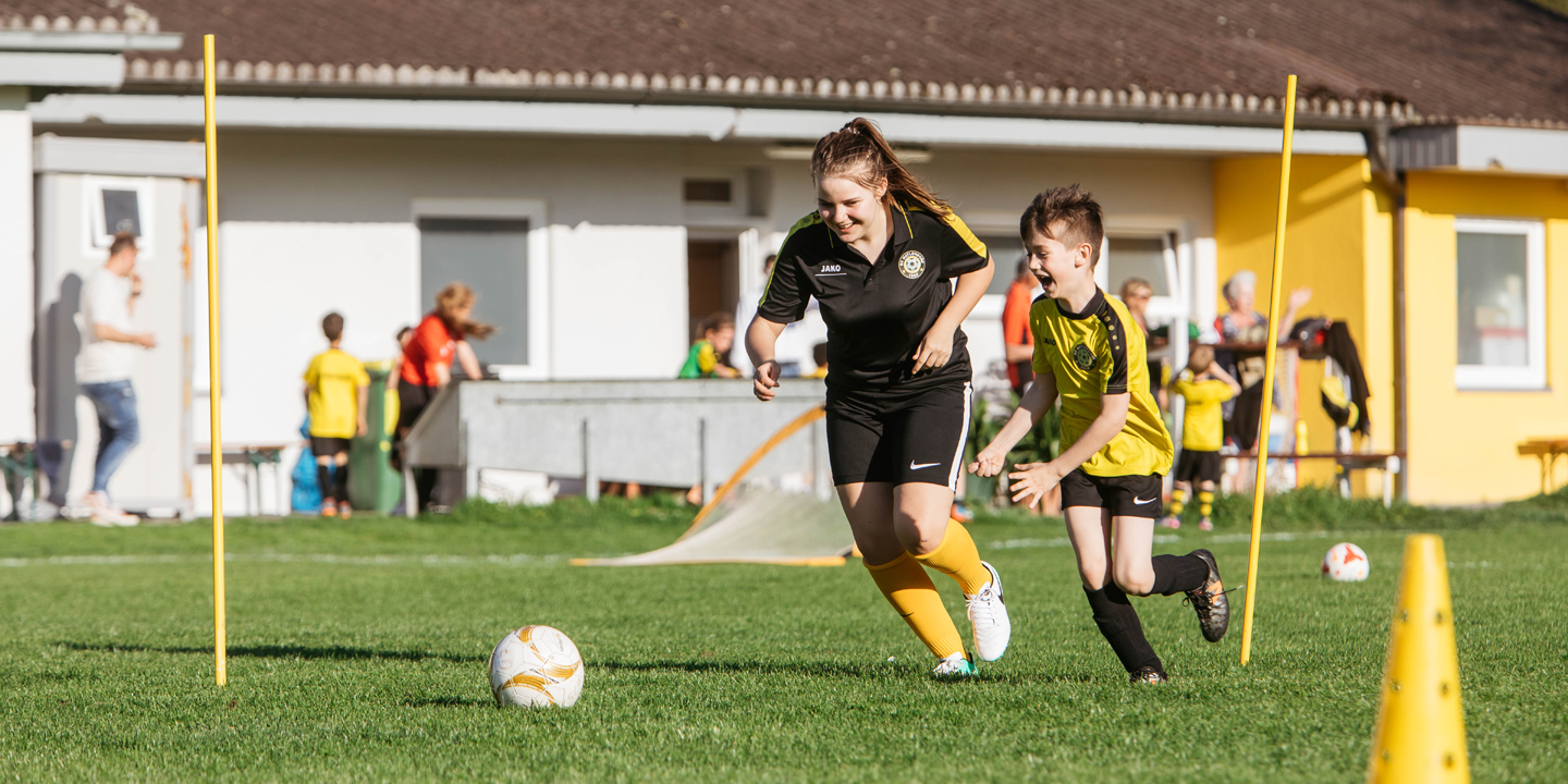 Jugendliche beim Fußballspielen mit einem Buben.