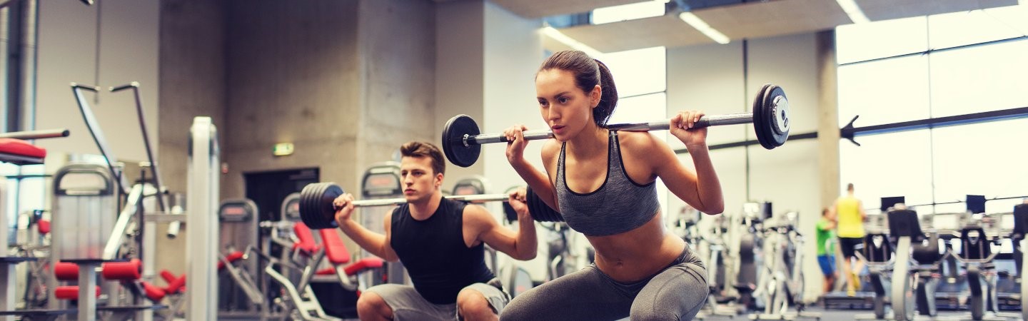 Junger Mann und junge Frauen trainieren im Fitnesscenter