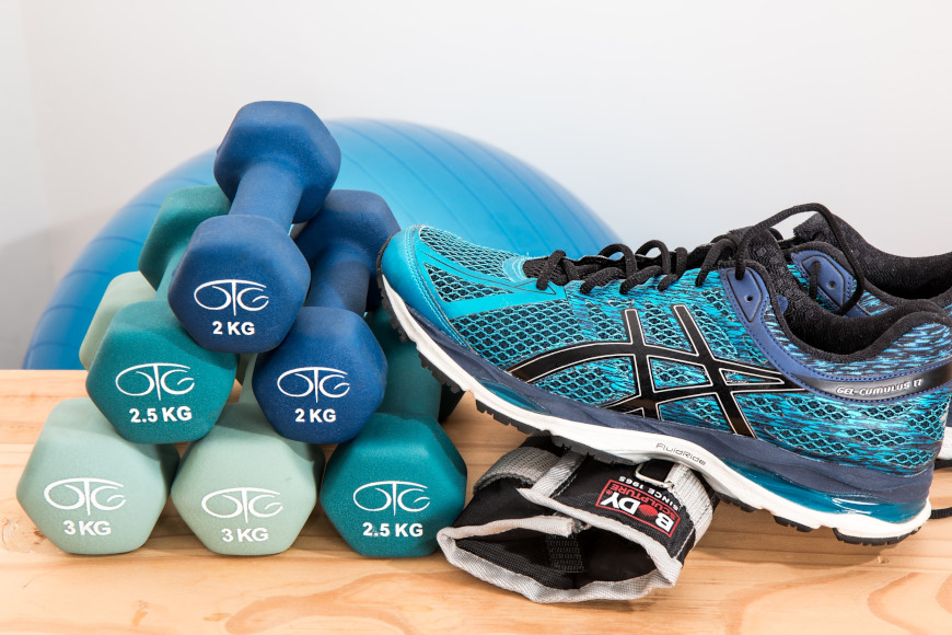 Hanteln und SPortschuhe, die auf einem Holzboden liegen