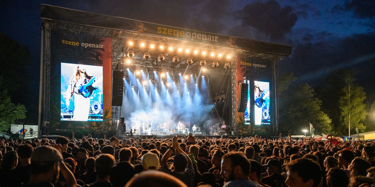 Eine Menschenmenge vor einer Openair-Bühne mit großen Bildschirmen