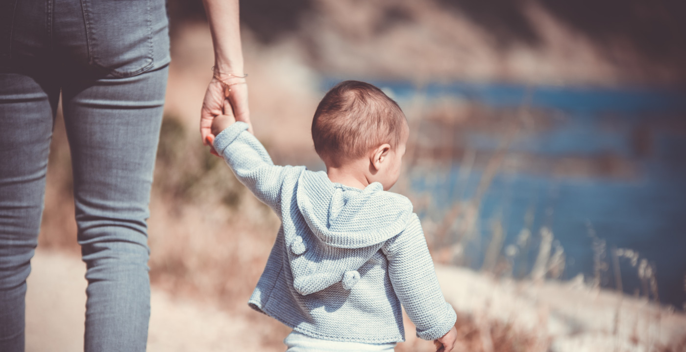 Ein Kind läuft an der Hand einer Person