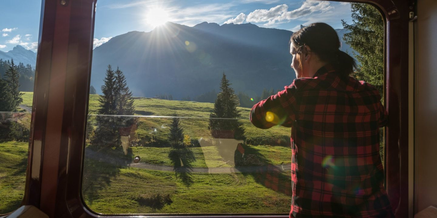 Eine frau schaut aus einem Zugfenster in die Berge