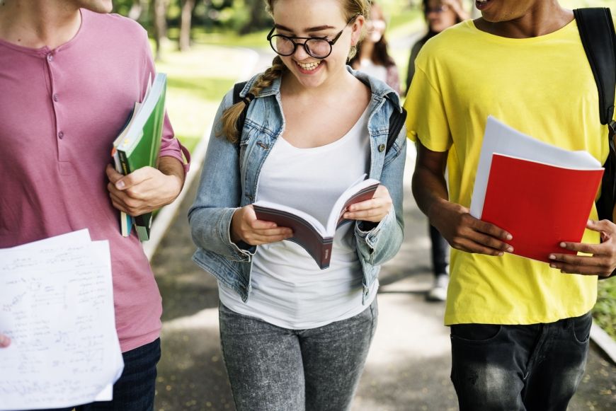 Eine Jugendliche lacht in einer Gruppe von Personen, die alle Bücher in der Hand halten.