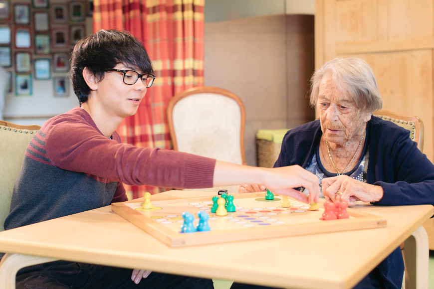 Ein jugne Mann spielt mit einer älteren Dame Mensch ärgere dich nicht.