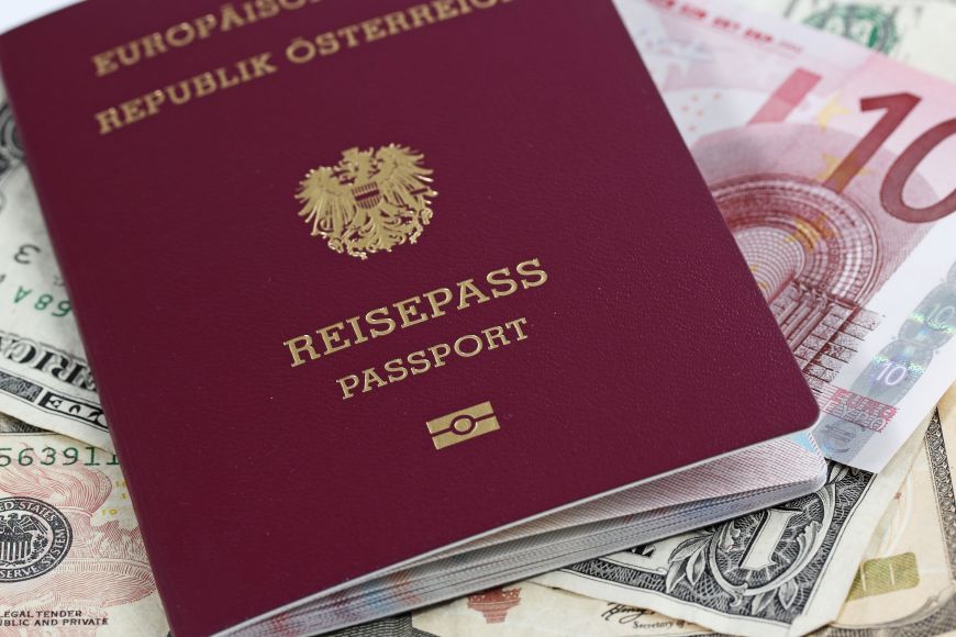 Ein österreichischer Reisepass, der auf verschiedenen ausländischen Geldnoten leigt.