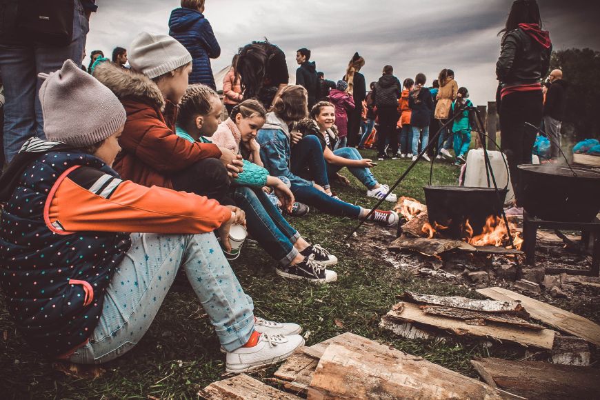 Jugendliche sitzen im Freien vor einem Lagerfeuer