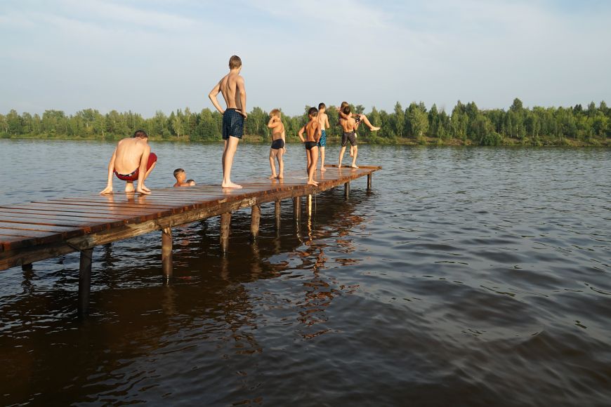 Jugendliche an einem Badesteg, die ins Wasser springen