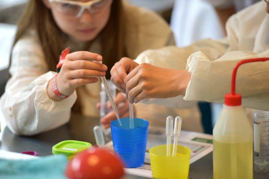 Kinder experementieren mit Bechern und Pipetten