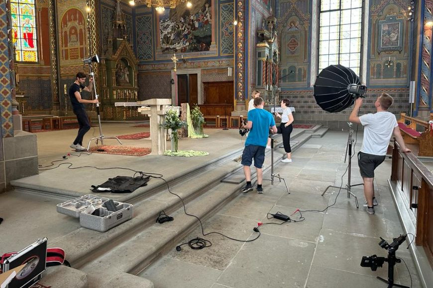 Jugendliche bauen in einer Kirche Schweinwerfer im Altarraum auf.