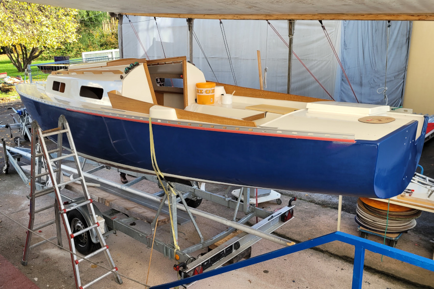 Blaues Segelboot in einer Werkstatt.