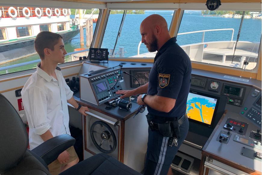 Ein Polizist erklärt Teo das Polizeiboot und die Geräte.